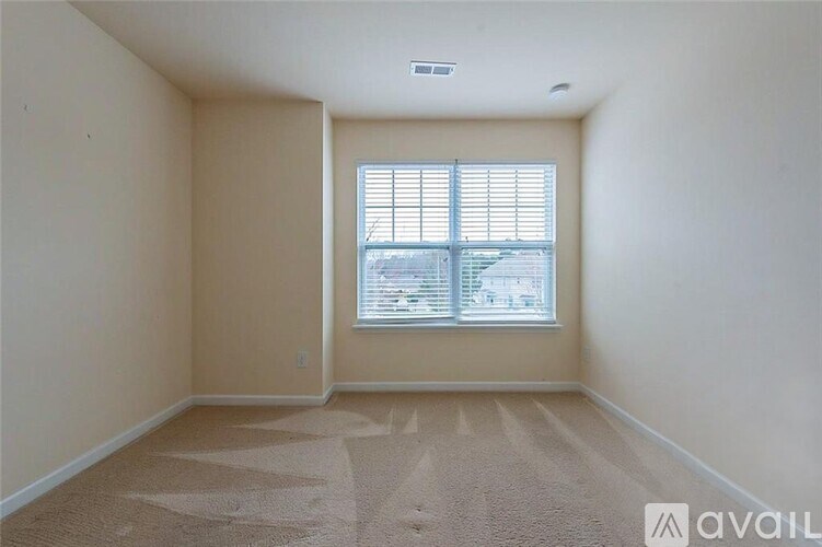 A room with a carpeted floor and a window with blinds.