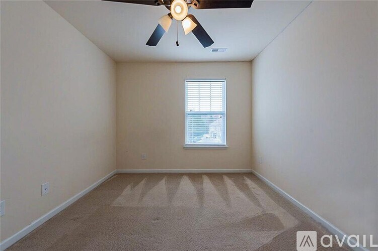 A room with a fan, carpet, and a window.