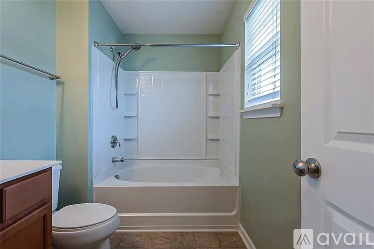 A bathroom with a toilet, bathtub, and a window.