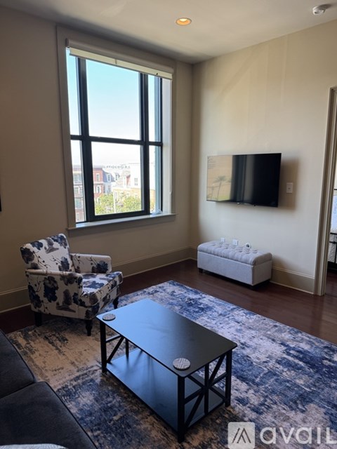 A living room with a black coffee table and a blue patterned rug.