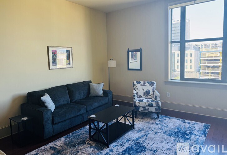 A living room with a black couch, a blue patterned chair, and a black coffee table.
