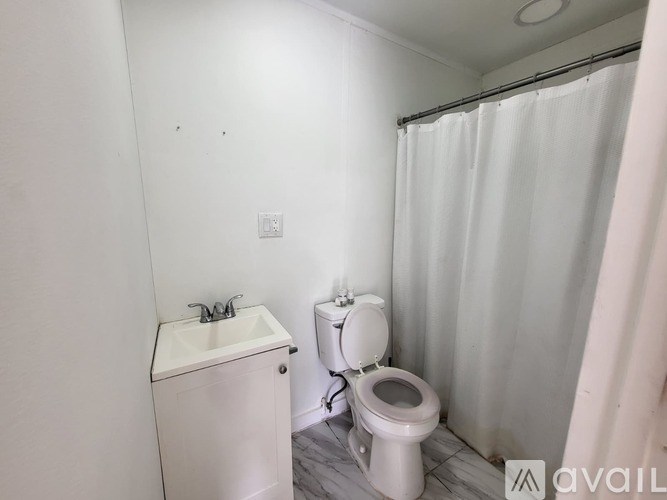 A small bathroom with a toilet, sink, and shower curtain.