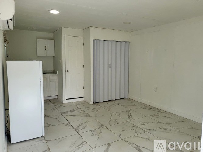 A kitchen with a white refrigerator and marble flooring.