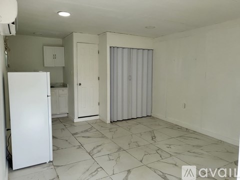 A kitchen with a white refrigerator and marble flooring.