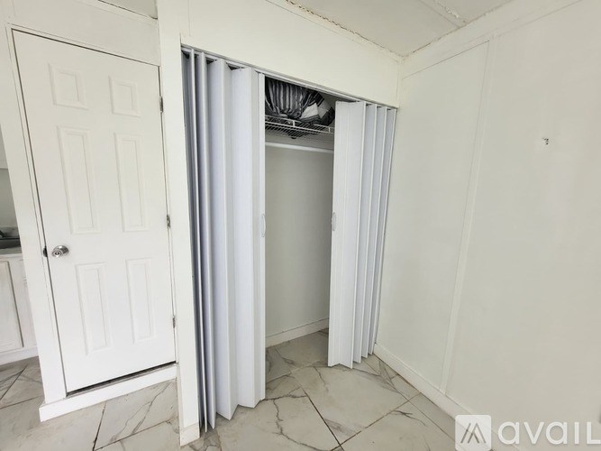 A white door is open to a room with a white curtain.