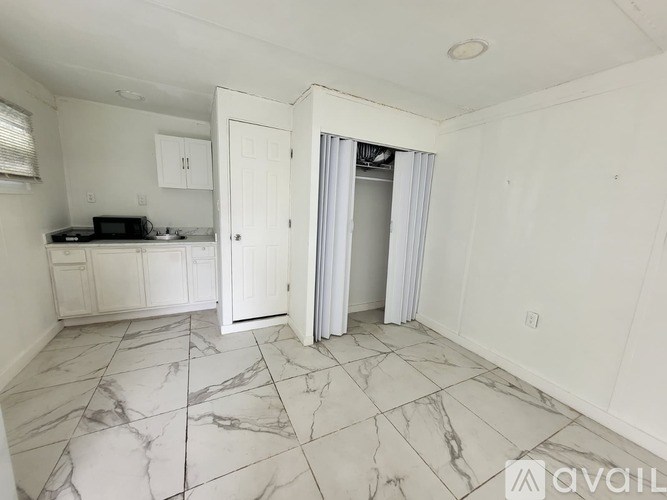 A kitchen with white cabinets and a marble floor.