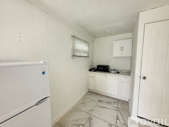 A kitchen with a white fridge and white cabinets.