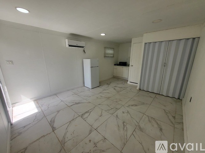 A room with a marble floor and a white refrigerator.