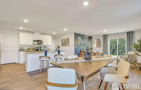 A modern kitchen with white cabinets and a dining area with a wooden table and chairs.