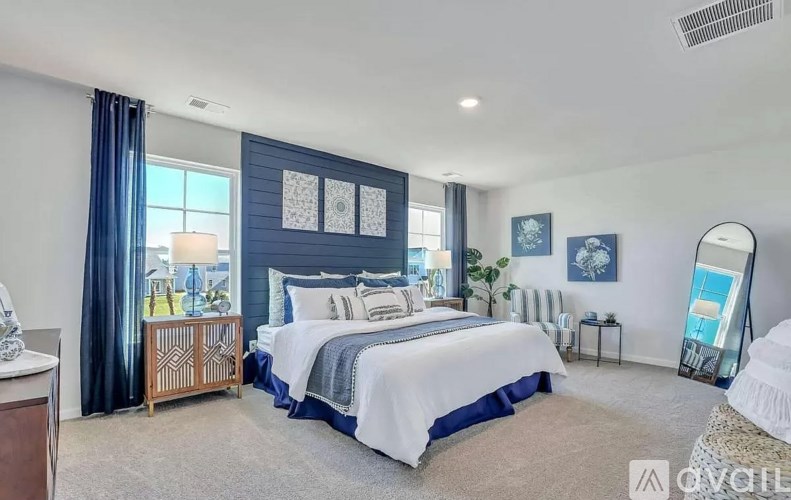 A bedroom with a large bed and a window with curtains.