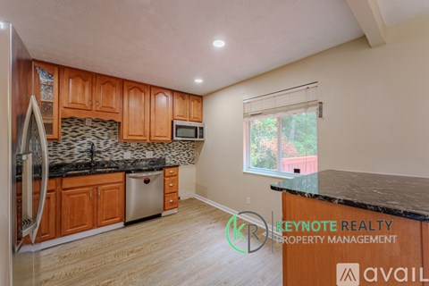 A kitchen with wooden cabinets and a black granite countertop.