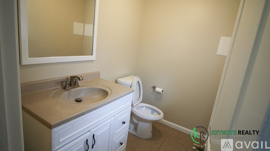 A bathroom with a sink, toilet, and mirror.