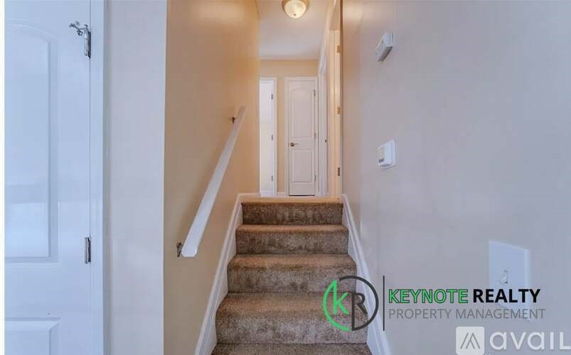A staircase with a carpeted runner and a white door at the top.