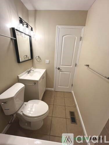 A bathroom with a toilet, sink, mirror, and a door.