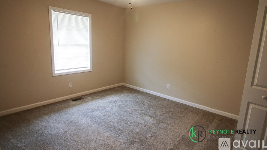 A room with a window and a carpeted floor.