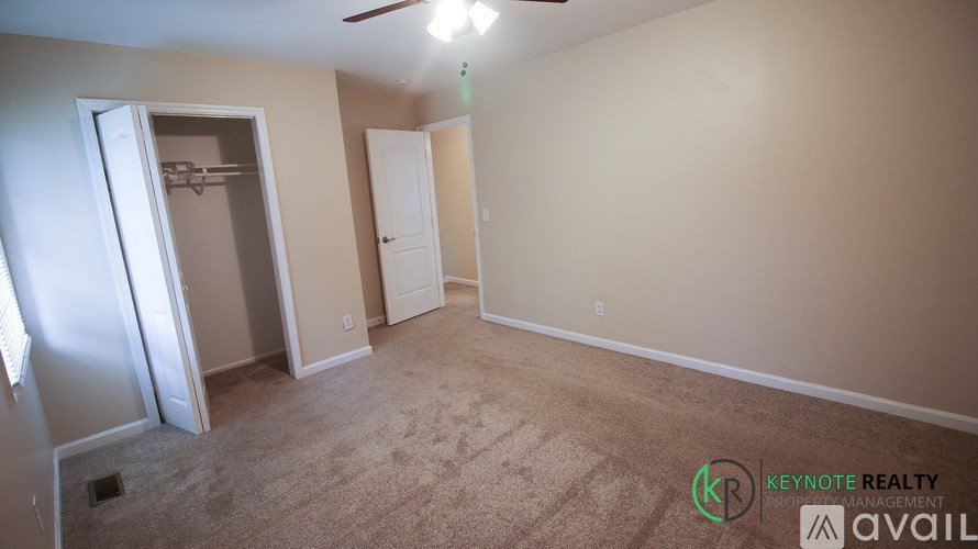 A room with a carpeted floor and a ceiling fan.