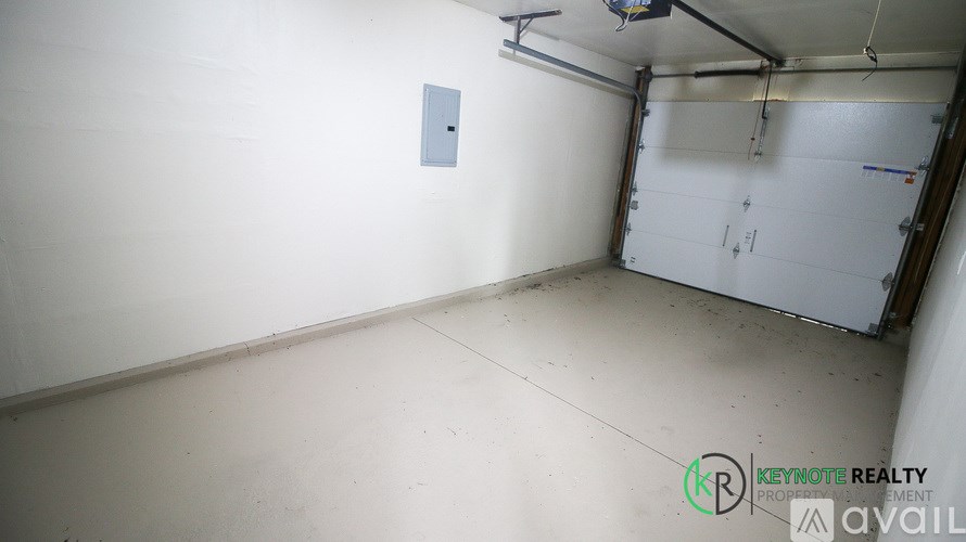 A white wall with a switchboard and a white door in a room.
