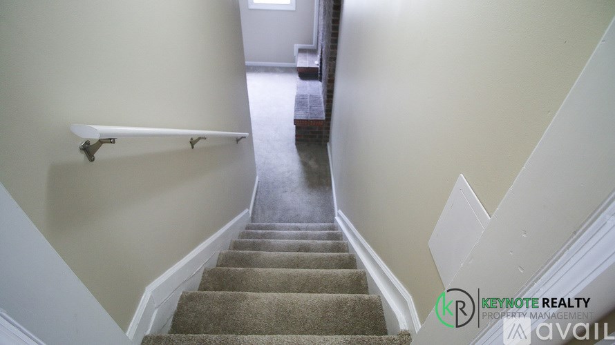 A staircase with a carpeted runner and a metal handrail.