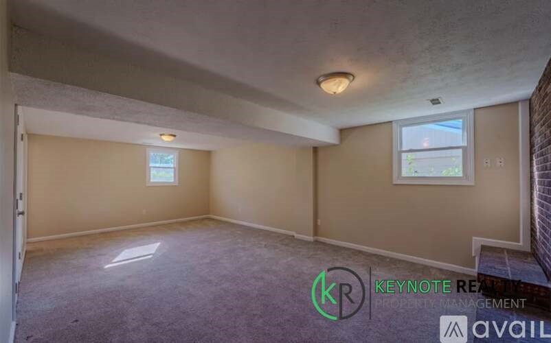 A room with a carpeted floor and a window with a view of a building outside.