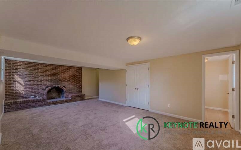 A room with a brick fireplace and a carpeted floor.