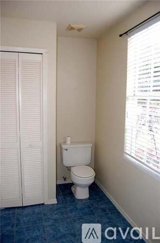 A white toilet in a small bathroom with a blue floor.