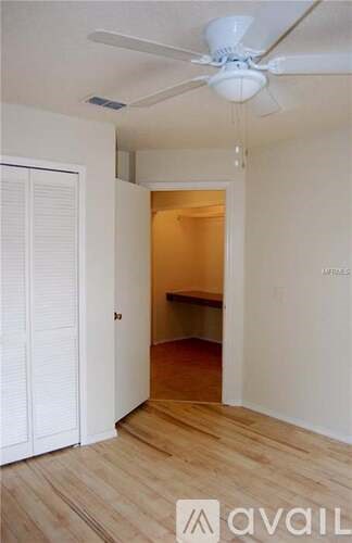 A room with a ceiling fan and a door leading to another room.
