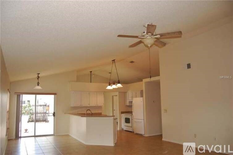 A kitchen with white cabinets and a refrigerator is available for rent.