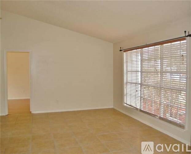 A room with a window covered by blinds and a tiled floor.