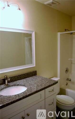 A bathroom with a sink, mirror, toilet and a shower.