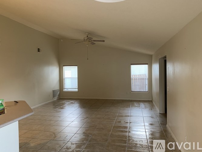A spacious room with tiled flooring and a ceiling fan.