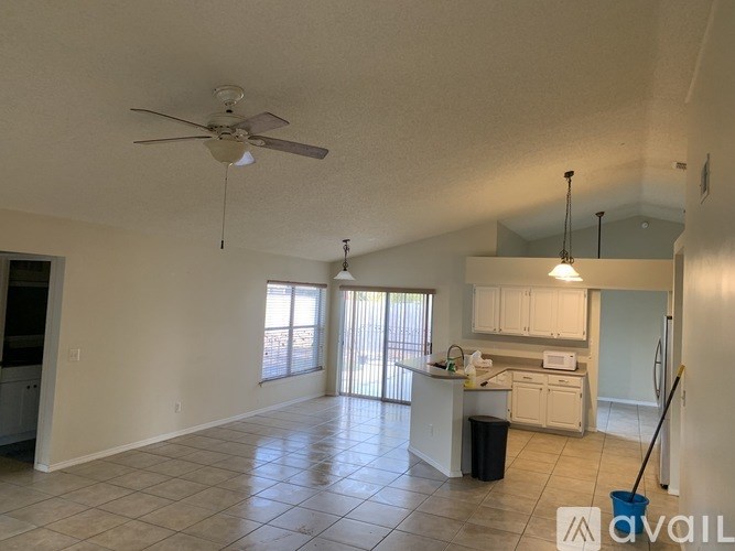 A spacious living room with a ceiling fan and sliding glass doors.