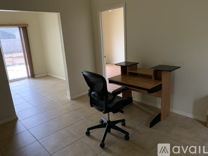 A black chair is in front of a desk with a laptop on it.