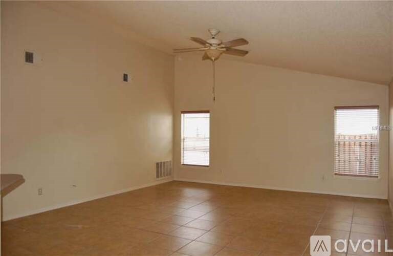 A room with a ceiling fan and two windows.