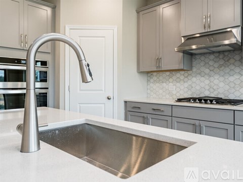 A modern kitchen with a stainless steel sink and faucet.