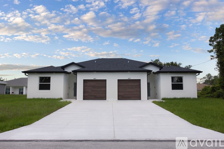 A modern house with a large driveway in front.