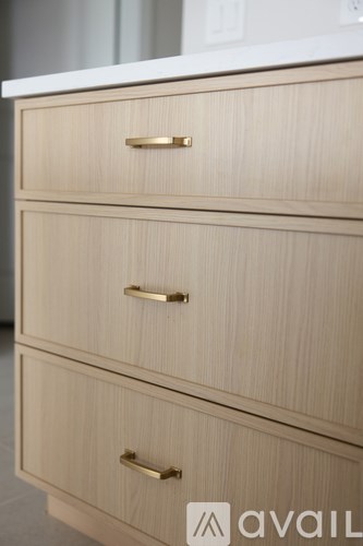 Three drawers with brass handles in a light wood finish.