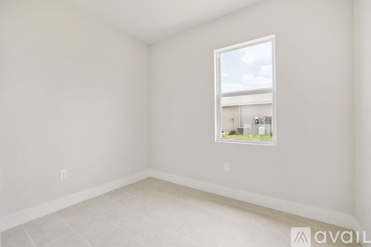 A room with a window showing a view of a house.