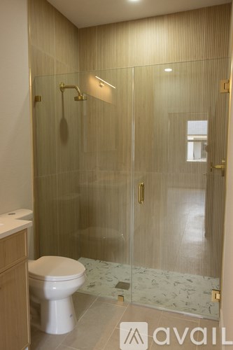 A bathroom with a toilet, a glass shower stall, and a marble floor.