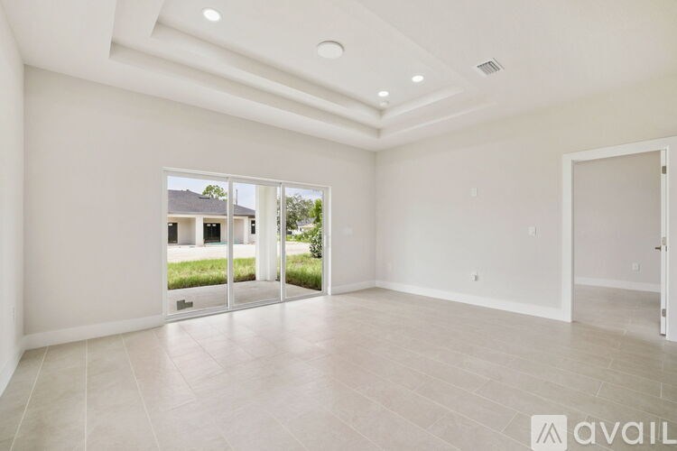A spacious room with a view of a house through the glass doors.