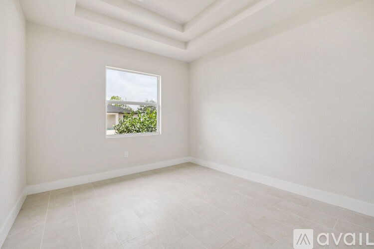 A room with a window showing a view of a building and trees.