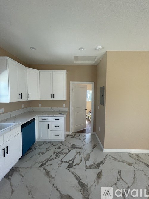 A kitchen with marble flooring and white cabinets.