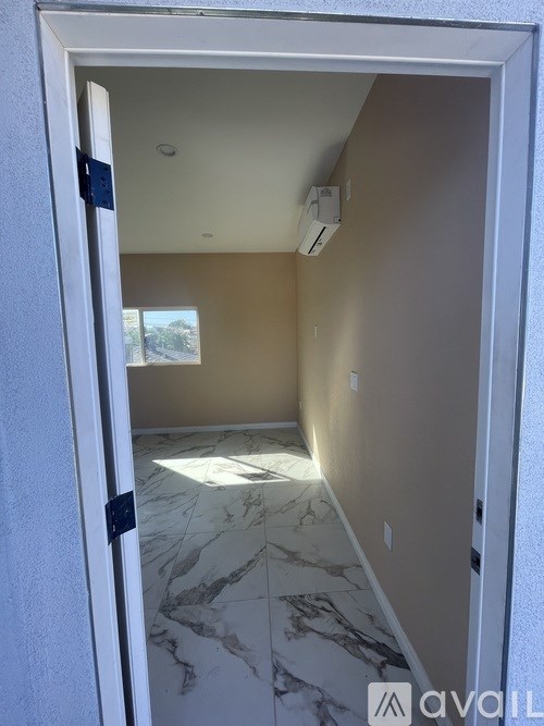 A hallway with marble flooring and a wall-mounted air conditioner unit.