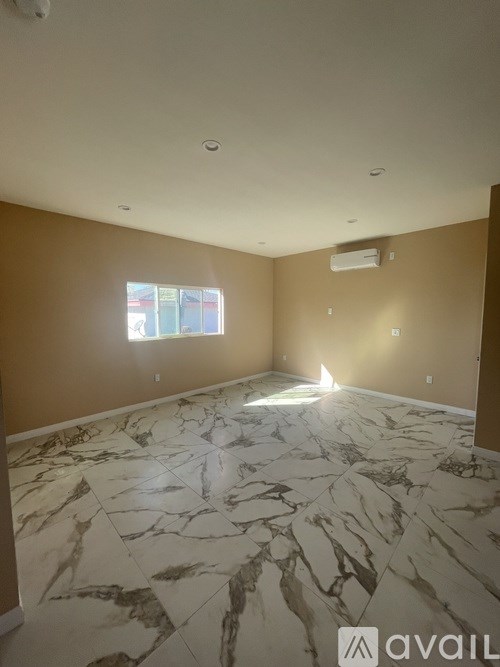 A room with marble flooring and a window letting in sunlight.