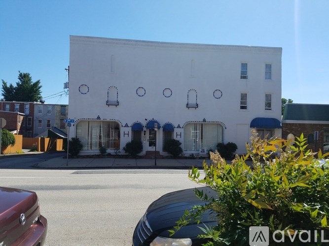 A white building with blue trim and a sign that says "AVAILABLE" in front of it.