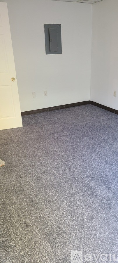 A room with a carpeted floor and a window with blinds.