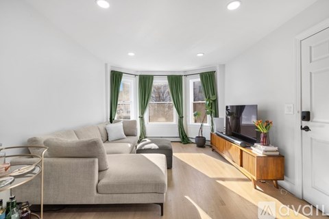 A living room with a beige couch, a wooden coffee table, and a television on a wooden stand.