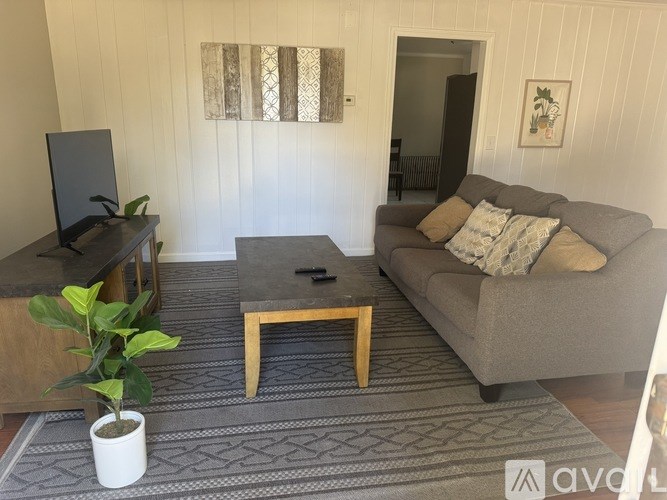 A living room with a grey couch, a coffee table, and a television.