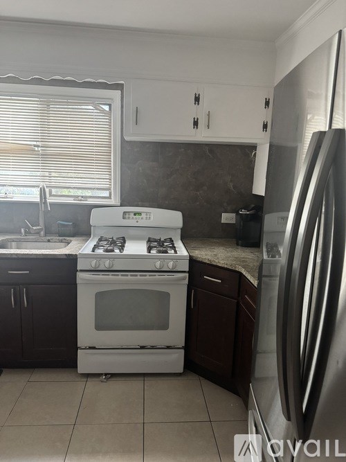 A kitchen with a stove, sink, and refrigerator.
