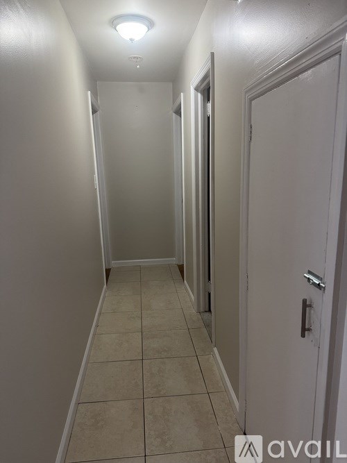A long hallway with white walls and tile flooring.