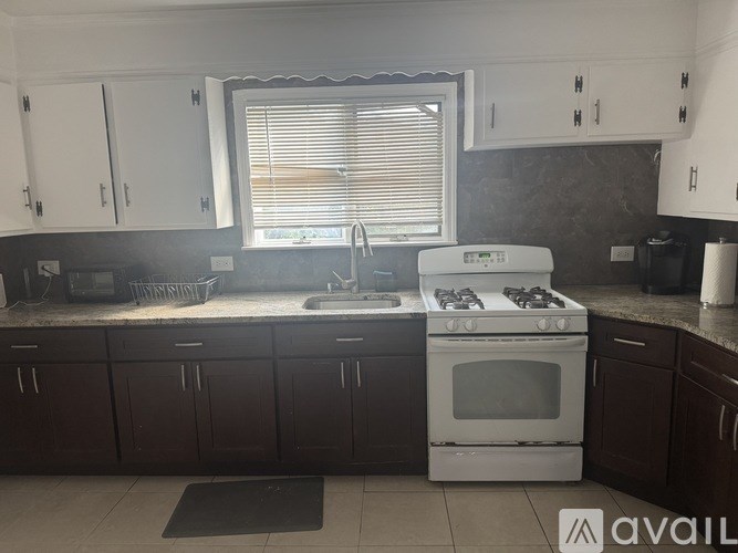 A kitchen with white appliances and dark brown cabinets.